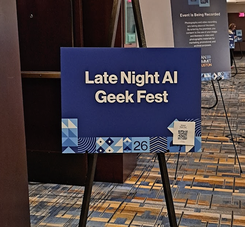 A conference sign on an easel reading “Late Night AI Geek Fest” displayed in a convention center hallway