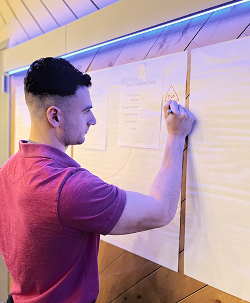 Participant engaging in Six Sigma simulation during SimWeek, drawing on a white sheet of paper